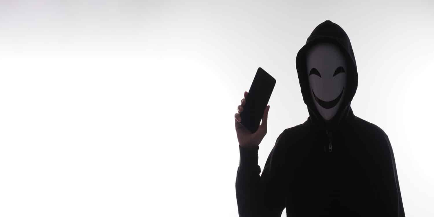 hacker mascherato cappuccio nero smartphone truffe telefoniche